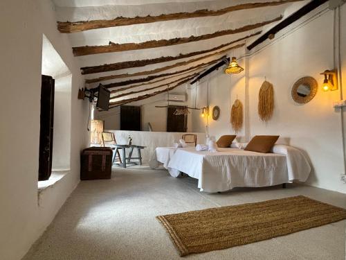 a white room with two beds and a table at Casa De La Aguadora in Iznatoraf