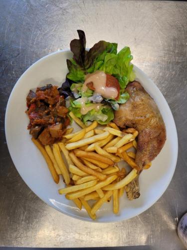 a plate of food with french fries on a table at Le petit Montmartre in Dinard