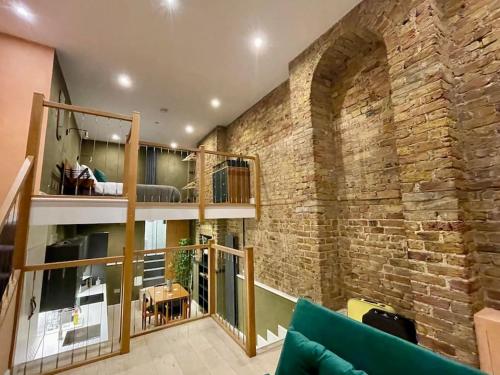 um quarto com uma parede de tijolos e um sofá verde em Exposed Brick Flat Finsbury Park em Londres