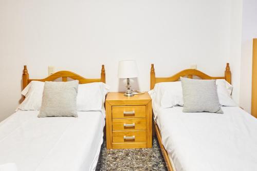 two beds with white sheets and a nightstand with a lamp at EL RINCÓN VERDE in Puerto de Sagunto