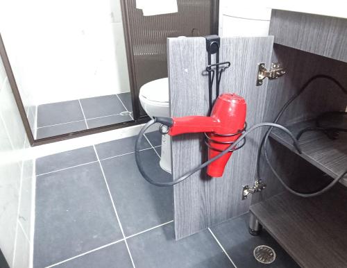 a bathroom with a red blow dryer attached to a toilet at Hermosa vivienda central en el mejor lugar de Medellín in Envigado