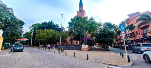 a street with cars driving down a street with a church at Hermosa vivienda central en el mejor lugar de Medellín in Envigado