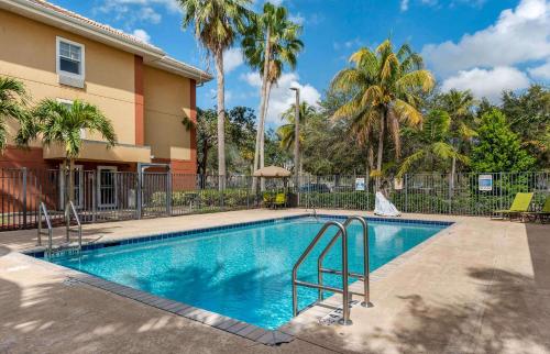 a swimming pool in front of a building with palm trees at Extended Stay America Suites - Fort Lauderdale - Plantation in Plantation