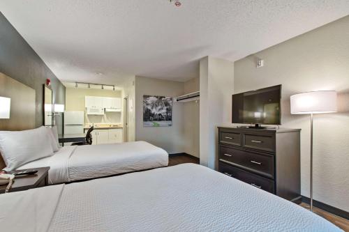 a hotel room with two beds and a flat screen tv at Extended Stay America Suites - Miami - Airport - Blue Lagoon in Miami