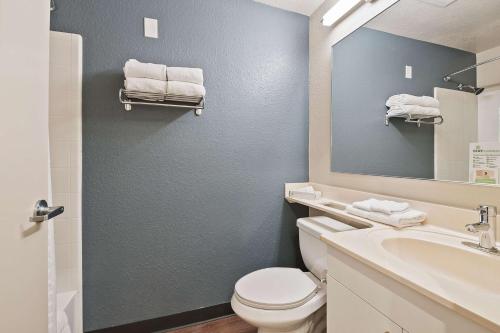 a bathroom with a toilet and a sink and a mirror at Extended Stay America Suites - Miami - Airport - Blue Lagoon in Miami