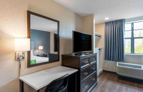 Habitación de hotel con escritorio, TV y espejo. en Extended Stay America Premier Suites - Miami - Airport - Doral - 87th Avenue South en Miami
