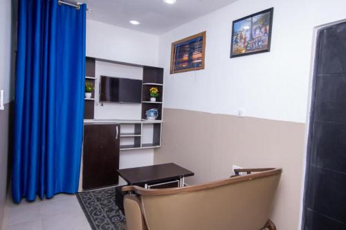 a living room with a table and a blue curtain at Wisdom Villa in Kumasi
