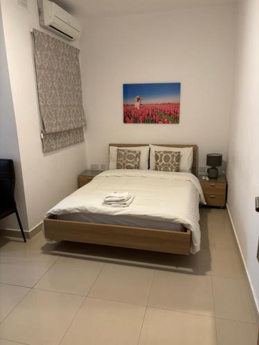 een slaapkamer met een bed en een schilderij aan de muur bij Belmonte Flat in Sliema