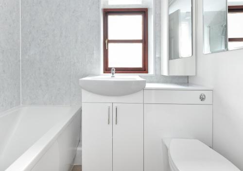 a white bathroom with a sink and a mirror at Trefaes Bach in Abersoch