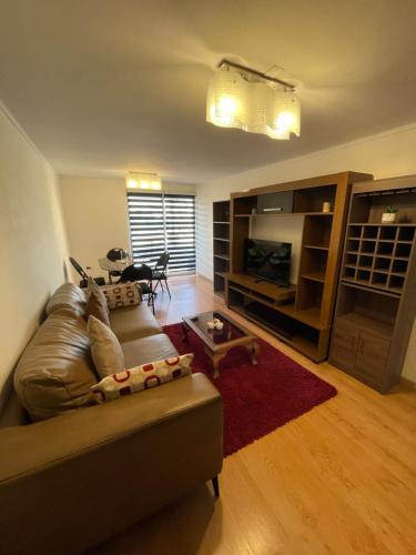 sala de estar con sofá de cuero y TV en Hermoso Depto Centrico, en Rancagua