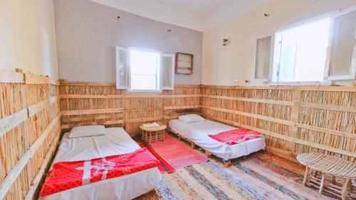 two beds in a room with wooden walls at هوستل أجبناخ إنشالي Hostel Agbenakh Inshaly in Siwa