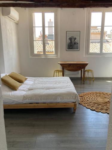 une chambre avec un lit, une table et des fenêtres dans l'établissement La Maison sur les Toits, à Aix-en-Provence