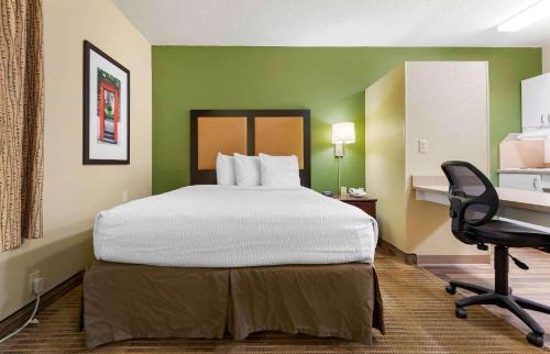 a large bed in a room with a desk and a chair at Extended Stay America Suites - Rochester - Greece in Greece