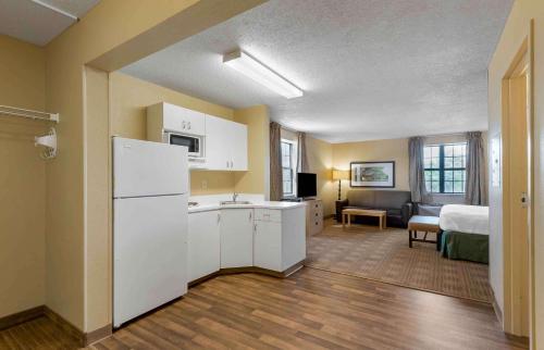 a kitchen with a white refrigerator and a bedroom at Extended Stay America Suites - Buffalo - Amherst in Amherst