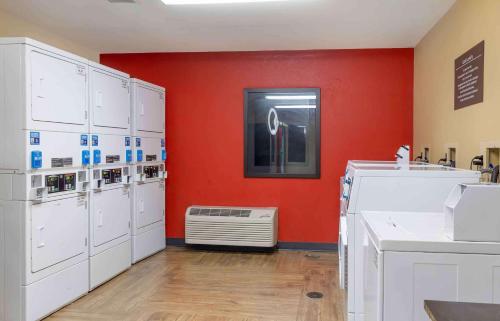 Extended Stay America Suites - Providence - Warwick في وارويك: غرفة غسيل مع غسالات بيضاء وجدار احمر