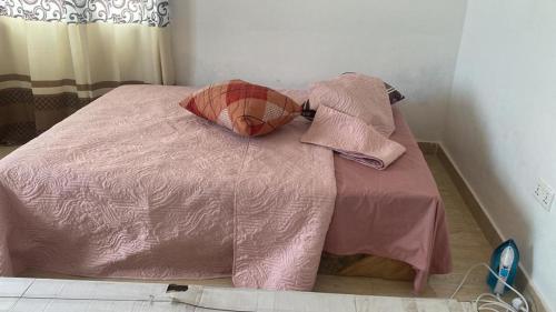 a pink bed with pillows on it in a bedroom at Charming 1-Bed Apartment in Accra in New Weija