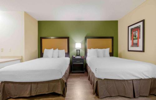 two beds in a hotel room with green walls at Extended Stay America Suites - Syracuse - Dewitt in East Syracuse