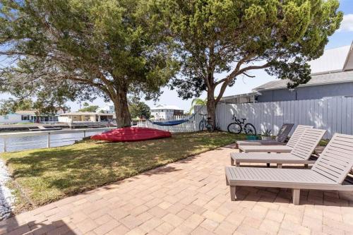 a patio with two white chairs and a tree at Waterfront oasis with NEW POOL and kayaks in Hernando Beach