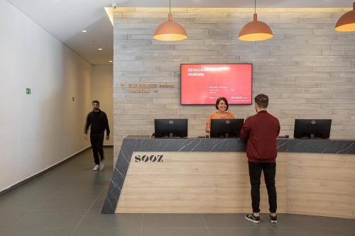 two people standing at a reception counter in a lobby at Sooz Hotel Collection in Sao Paulo