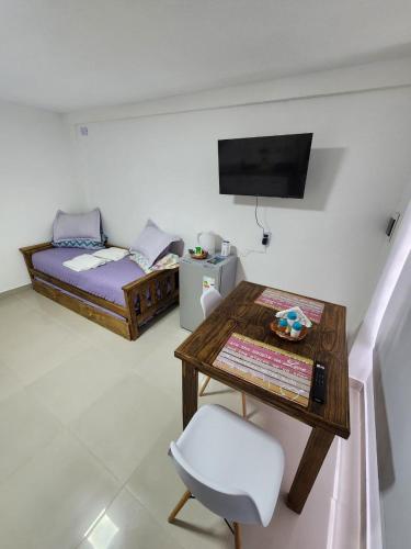 a room with a table and a bed and a television at JVL Neuquen in Neuquén
