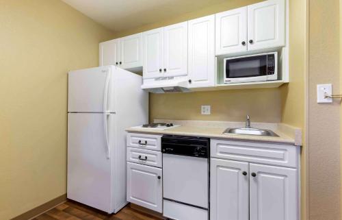 La cuisine est équipée de placards blancs et d'un réfrigérateur blanc. dans l'établissement Extended Stay America Suites - Washington, DC - Fairfax, à Fairfax