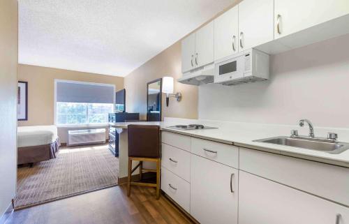 a kitchen with white cabinets and a sink and a bed at Extended Stay America Suites - Washington, DC - Tysons Corner in Tysons Corner