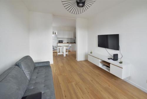 een woonkamer met een bank en een flatscreen-tv bij Duplex Villemoisson sur orge avec jardin in Villemoisson-sur-Orge