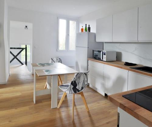 een witte keuken met een tafel en een witte koelkast bij Duplex Villemoisson sur orge avec jardin in Villemoisson-sur-Orge