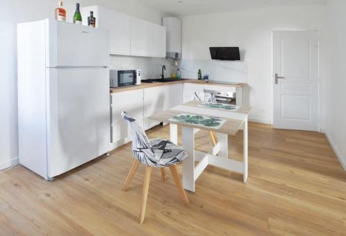 een witte keuken met een tafel en een stoel bij Duplex Villemoisson sur orge avec jardin in Villemoisson-sur-Orge