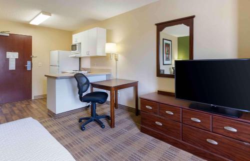 a hotel room with a desk and a tv and a chair at Extended Stay America Select Suites - Des Moines - Urbandale in Clive