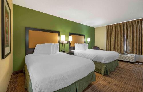 two beds in a hotel room with green walls at Extended Stay America Suites - Champaign - Urbana in Champaign
