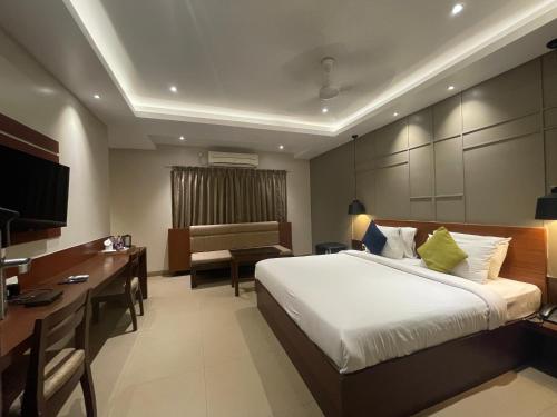 ein Hotelzimmer mit einem großen Bett und einem Schreibtisch in der Unterkunft Five Elements in Visakhapatnam