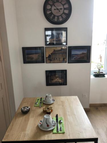 a dining room table with a clock on the wall at La petite Irlande in Auderville