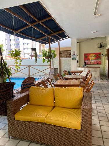 a couch on a patio with a table and chairs at THEMATIC POUSADA in João Pessoa