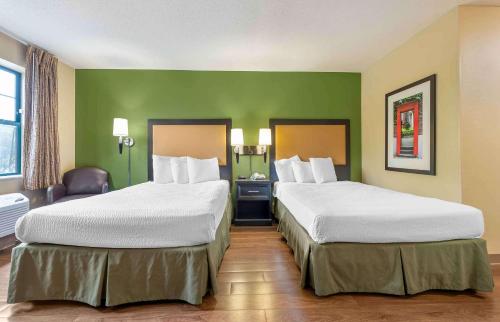 two beds in a hotel room with green walls at Extended Stay America Suites - Bloomington - Normal in Bloomington