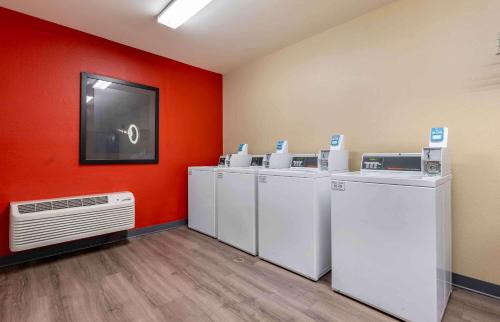 a laundry room with white washers and dryers against a red wall at Extended Stay America Suites - Bloomington - Normal in Bloomington