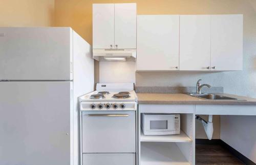 a white kitchen with a stove and a microwave at Extended Stay America Suites - Chicago - O'Hare - Allstate Arena in Des Plaines
