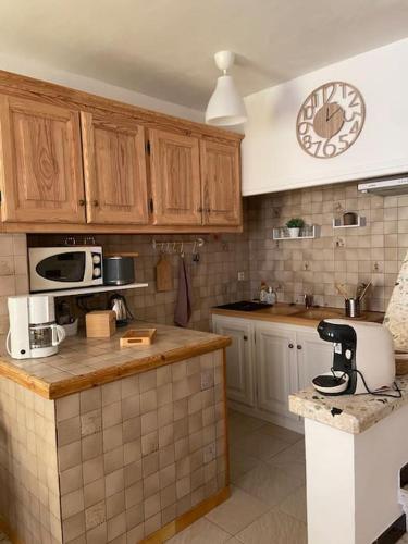 une cuisine avec des armoires en bois et une horloge au mur dans l'établissement Maison au cœur du village de Gruissan, à Gruissan