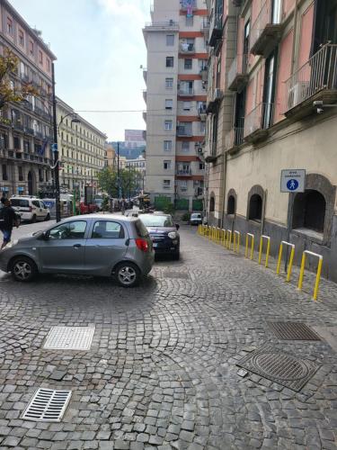 two cars parked on a cobblestone street with buildings at MEGARA HOUSE in Naples