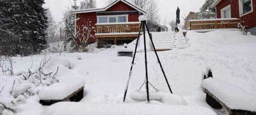 un patio cubierto de nieve frente a una casa en Lila Stuga, en Väja