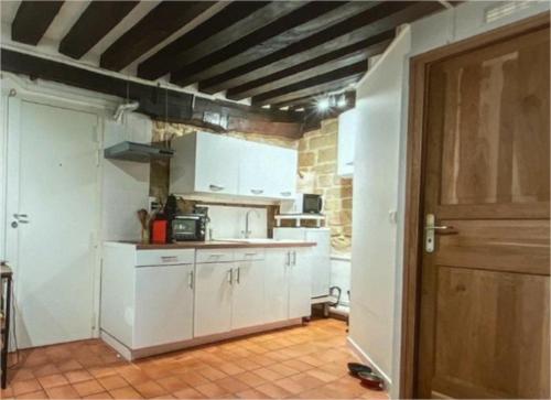 - une cuisine avec des placards blancs et une porte en bois dans l'établissement Au Centre historique de Paris (Marais), à Paris