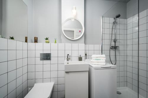 a white bathroom with a sink and a mirror at Apart D&K Blisko Stadionu Narodowego in Warsaw