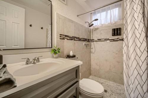 Baño blanco con lavabo y aseo en Adorable 2-Bedroom Modern Basement en Denver