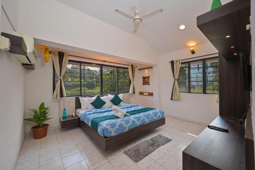 a bedroom with a bed in a room with windows at Great Escape Villa by Tropicana Stays in Lonavala
