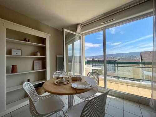 une salle à manger avec une table et des chaises et une grande fenêtre dans l'établissement CHEZ JOYCE Appartement cocooning, à Lons-le-Saunier