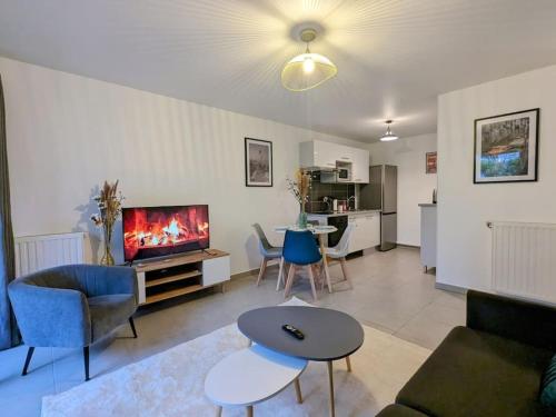 un salon avec un canapé, une télévision et une table dans l'établissement Le Jardin du Tramway, 30 min de Paris, à Bezons