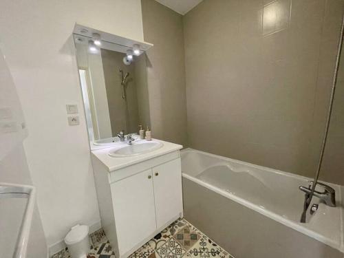 uma casa de banho branca com um lavatório e uma banheira em CHEZ JOYCE Appartement cocooning em Lons-le-Saunier