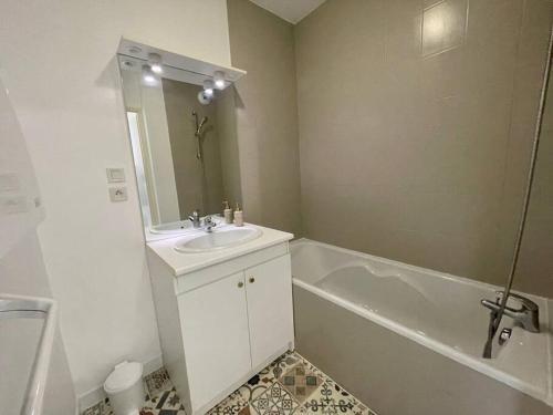 une salle de bain blanche avec un lavabo et une baignoire dans l'établissement CHEZ JOYCE Appartement cocooning, à Lons-le-Saunier
