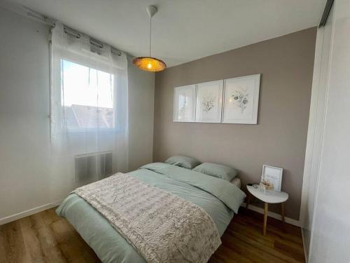 um quarto com uma cama, uma mesa e uma janela em CHEZ JOYCE Appartement cocooning em Lons-le-Saunier