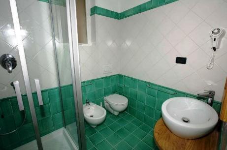 - une salle de bains verte et blanche avec lavabo et toilettes dans l'établissement Affittacamere Da Cesare, à Monterosso al Mare